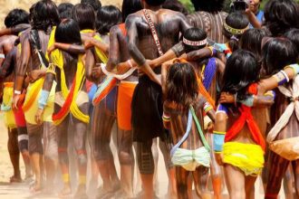 Indígenas da etnia Sururuá reunidos, com pinturas corporais e vestimentas tradicionais, em celebração.