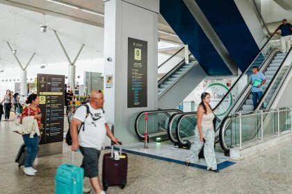 Interior do Aeroporto de Manaus com pessoas caminhando e escadas rolantes.