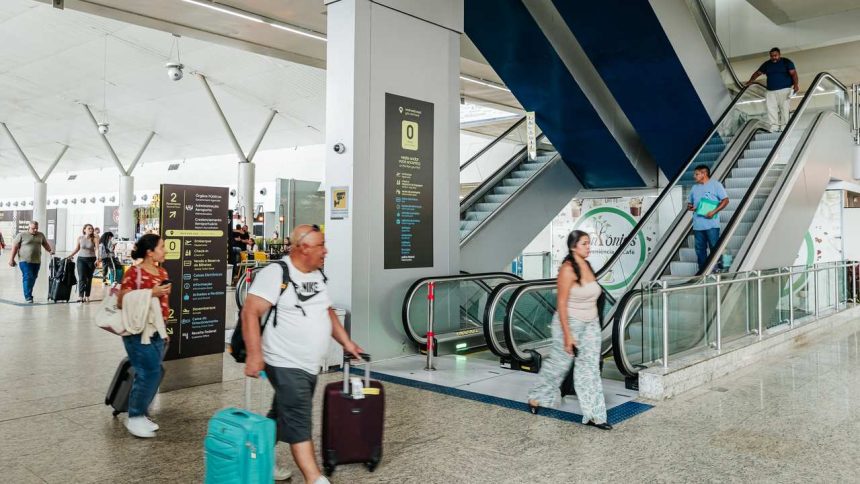 Interior do Aeroporto de Manaus com pessoas caminhando e escadas rolantes.