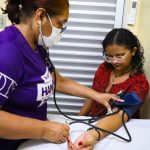 Médica aferindo pressão arterial em paciente durante consulta em Manaus