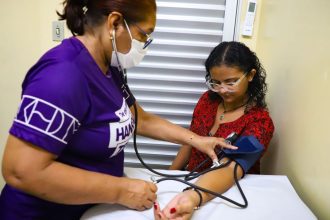 Médica aferindo pressão arterial em paciente durante consulta em Manaus