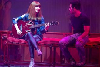 Mel Lisboa como Rita Lee tocando guitarra em espetáculo teatral.