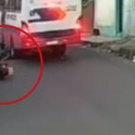 Motocicleta caída na rua após acidente ao desviar de buraco.
