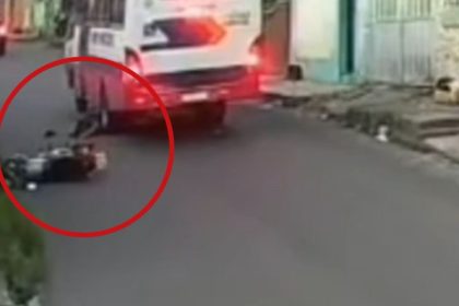 Motocicleta caída na rua após acidente ao desviar de buraco.