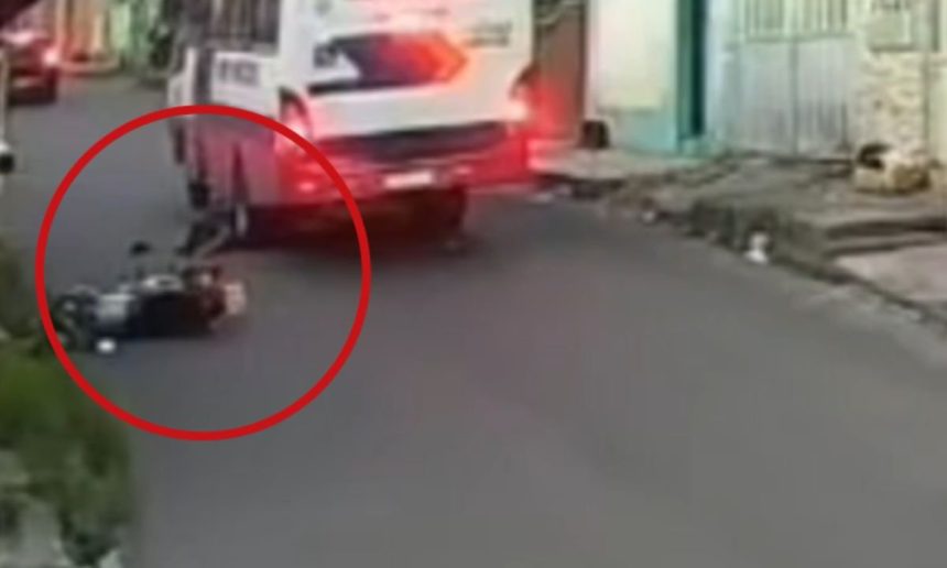 Motocicleta caída na rua após acidente ao desviar de buraco.