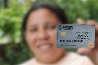 Mulher segurando cartão Auxílio Estadual Amazonas, com aviso sobre uso em apostas.