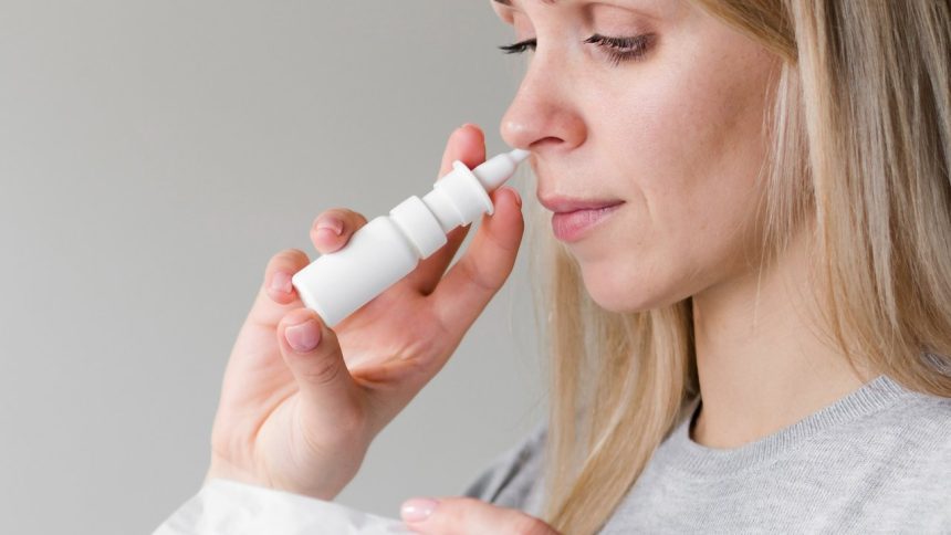 Mulher usando spray nasal para descongestão, seguindo orientações médicas.