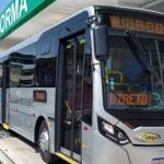 Ônibus estacionado em plataforma com letreiro indicando destino e inscrição "Veículo em teste".