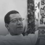 Padre Orlando Barbosa segurando uma vela cerimonial em preto e branco.