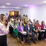 Palestrante em congresso de enfermagem oncológica, com público atento.