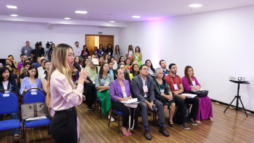 Palestrante em congresso de enfermagem oncológica, com público atento.