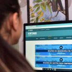 Pessoa olhando para a tela do computador com o site do Cetam aberto, anunciando cursos gratuitos EaD.