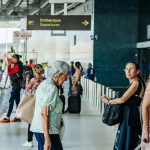 Pessoas em aeroporto, indicando embarque, com sinalizaรงรฃo de 'Departure'.