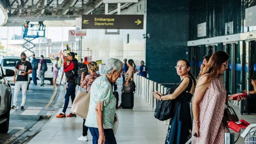 Pessoas em aeroporto, indicando embarque, com sinalização de 'Departure'.