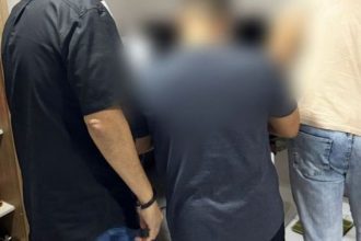 Pessoas em pé em uma sala, algumas com roupas escuras, outras com roupas claras.