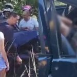 Pessoas reunidas perto de um veículo danificado. Cena possivelmente de acidente.