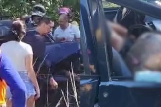 Pessoas reunidas perto de um veículo danificado. Cena possivelmente de acidente.