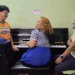 Pessoas sorrindo perto de um piano durante um concerto no Palácio da Justiça.