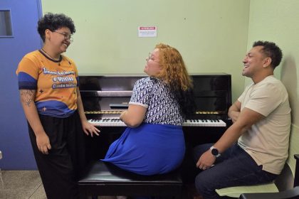 Pessoas sorrindo perto de um piano durante um concerto no Palácio da Justiça.