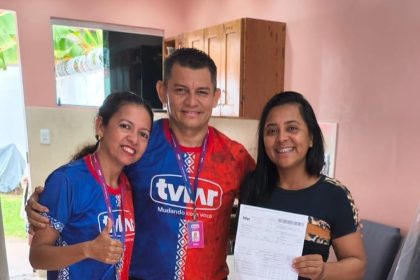 Pessoas sorrindo segurando comprovante da TVLAR em campanha de carro zero.