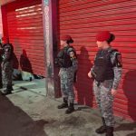 Policiais em frente a oficina mecânica, cena de crime.