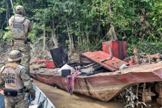 Policiais Federais em ação contra garimpo ilegal em rio da Amazônia. Embarcação destruída.