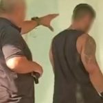 Policial aponta para homem preso por golpe