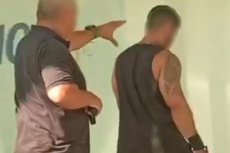 Policial aponta para homem preso por golpe
