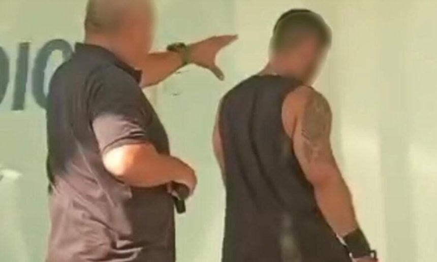 Policial aponta para homem preso por golpe