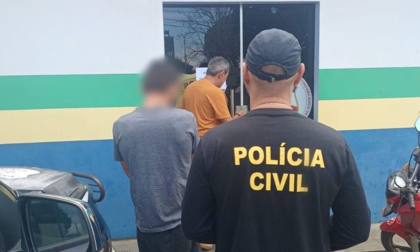 Policial civil com uniforme preto, em frente a uma delegacia, com presos.