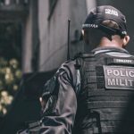 Policial militar de costas, vestindo uniforme tático