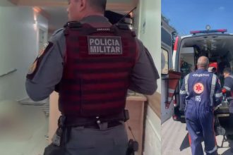 Policial militar em colete tático entra em uma clínica, ambulância estacionada do lado de fora.