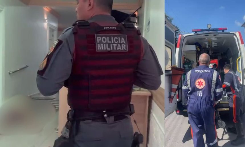 Policial militar em colete tático entra em uma clínica, ambulância estacionada do lado de fora.