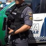 Policial militar em frente a viatura da Polícia Militar do Amazonas, com fuzil.