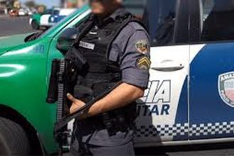 Policial militar em frente a viatura da Polícia Militar do Amazonas, com fuzil.