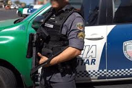 Policial militar em frente a viatura da Polícia Militar do Amazonas, com fuzil.