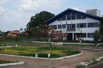 Prédio da prefeitura de Apuí, com jardim e céu azul.