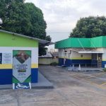 Prédios com cores verde, branco, azul e amarelo, com aviso sobre violência contra idosos e acessibilidade.