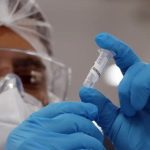 Profissional de saúde segurando tubo de amostra em laboratório.