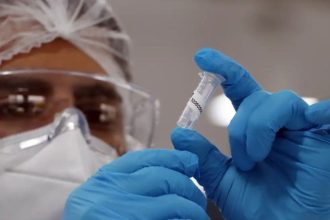 Profissional de saúde segurando tubo de amostra em laboratório.