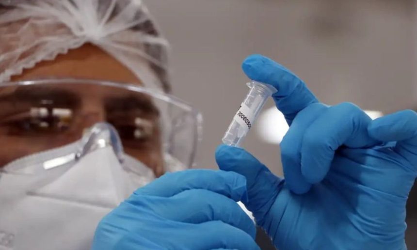 Profissional de saúde segurando tubo de amostra em laboratório.