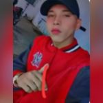 Rafael da Silva de Lima, procurado por homicídio, com jaqueta vermelha e boné preto.