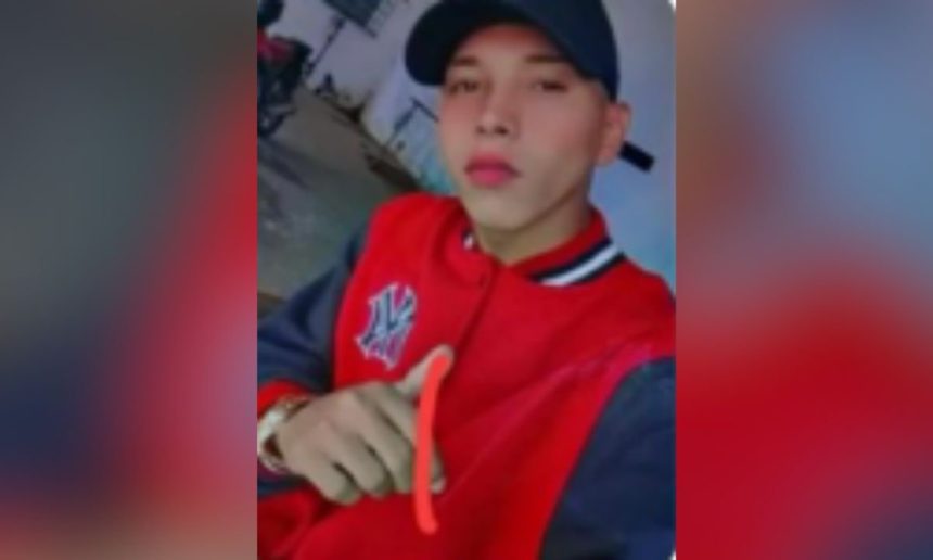 Rafael da Silva de Lima, procurado por homicídio, com jaqueta vermelha e boné preto.