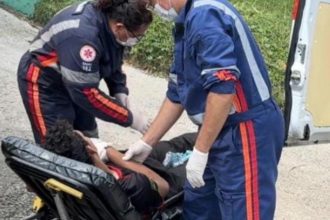 Socorristas atendem pessoa ferida em maca, perto de ambulância.