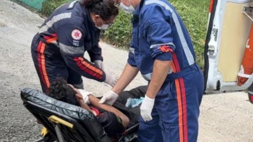 Socorristas atendem pessoa ferida em maca, perto de ambulância.