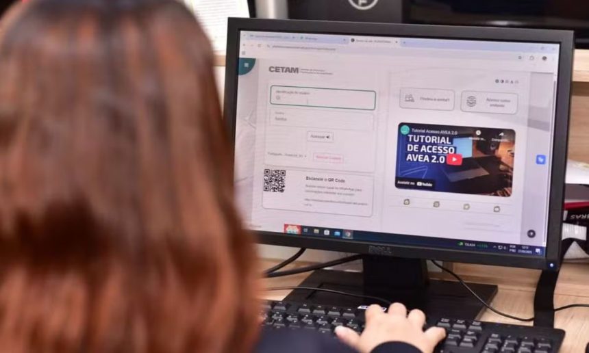 Tela de computador com inscrição Cetam para cursos de qualificação profissional, com pessoa usando o teclado.
