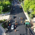 Vista aérea de obras de pavimentação na avenida Umberto Calderaro Filho em Manaus, com veículos e operários.