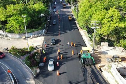 Vista aérea de obras de pavimentação na avenida Umberto Calderaro Filho em Manaus, com veículos e operários.