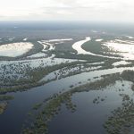 Vista aérea de um rio sinuoso e áreas alagadas na Amazônia.