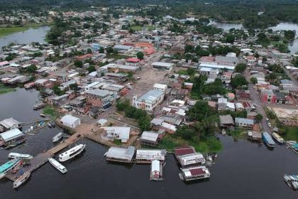 Vista aérea de uma cidade ribeirinha na Amazônia, com casas, barcos e rio. Manaquirii